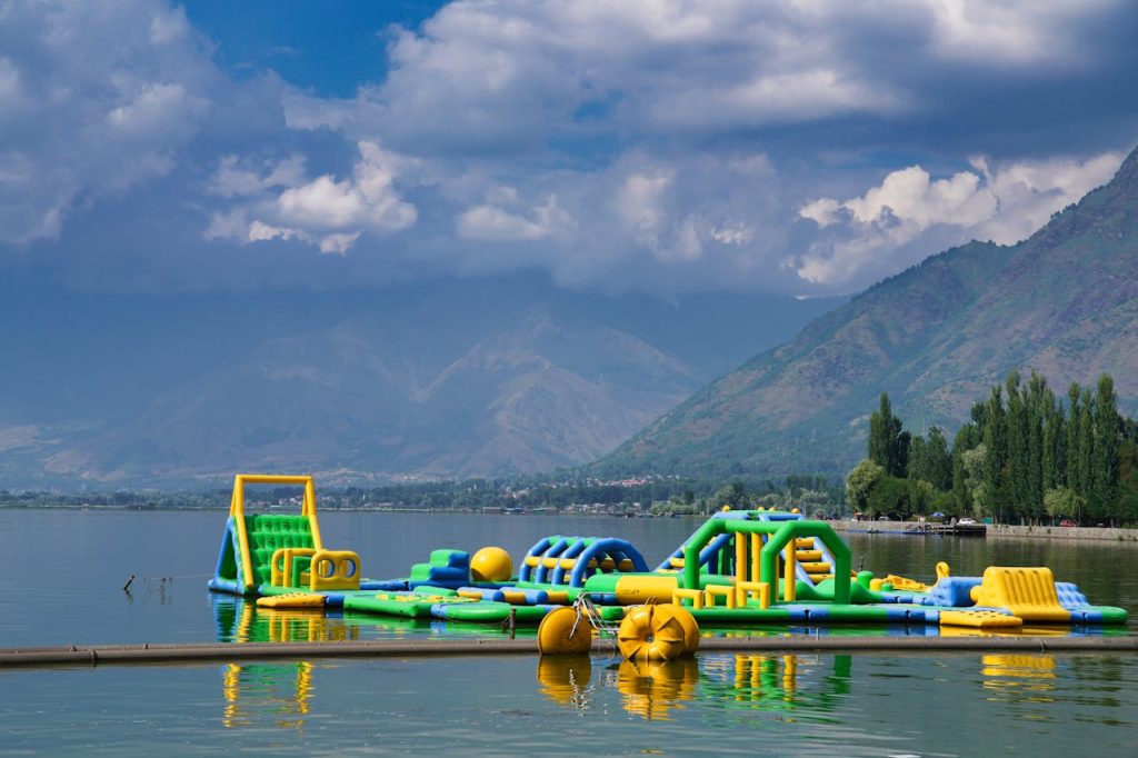Vibrant inflatable obstacle course on a tranquil alpine lake surrounded by mountains.